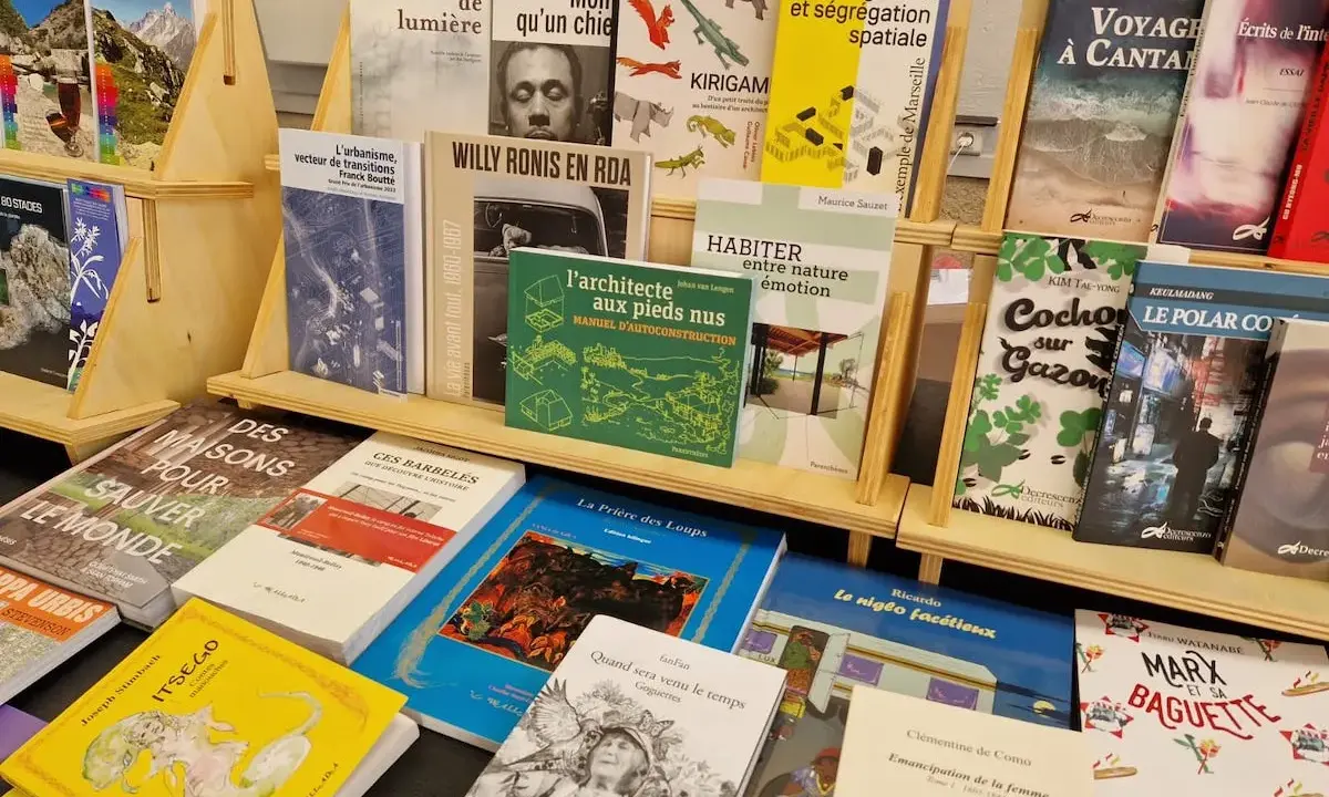 Des livres de divers éditeurs de livres, dont des ouvrages sur l'urbanisme, la photographie et la cuisine, sont exposés sur des étagères en bois.