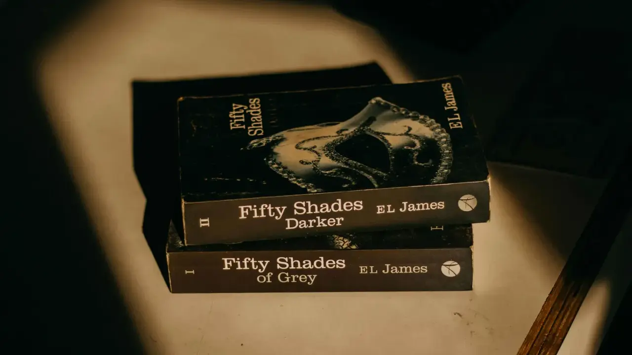 Trois livres de la série "Cinquante Nuances" d'EL James, dont "Cinquante Nuances de Grey", empilés, évoquant une histoire romantique.