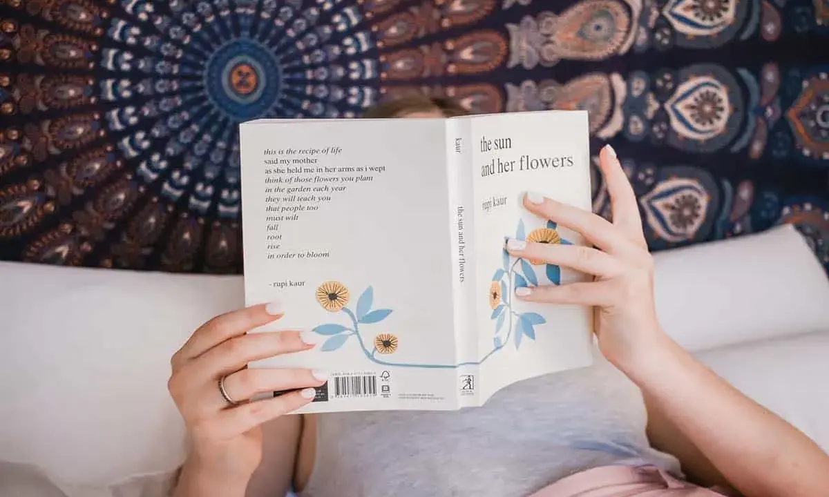 Une personne lit "the sun and her flowers" de Rupi Kaur, un livre de poésie. La dernière page d'un livre s'appelle la postface.