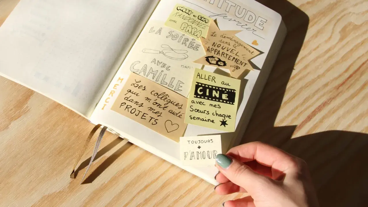 Un journal de gratitude avec des notes collées : "La soirée avec Camille", "Aller au cinéma avec mes sœurs", "Le déménagement dans le nouvel appartement".