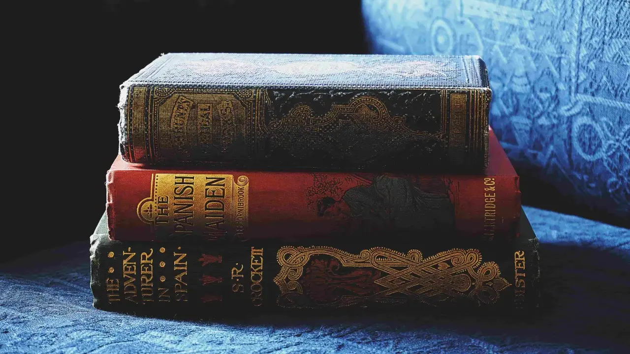 Pile de livres anciens aux couvertures ornées. Inspiré par ces reliures, découvrez comment créer la couverture d'un livre captivante.