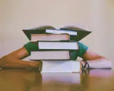 Une pile de livres sur la tête, symbolisant le poids de la connaissance et le sujet philo conscience.