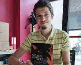 Un jeune écrivain souriant tient son livre "Les Peuples de la Terre".