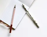 Deux stylos élégants, un rose à carreaux et un blanc à pois dorés, reposent sur un carnet ligné, prêts pour les éditions Balland manuscrit.