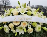 Un bouquet de fleurs blanches et crème, orné d'un ruban "À notre ami", symbolise une belle histoire d'amitié.
