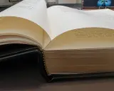 Gros plan sur des pages de livre ouvertes, révélant le texte imprimé et la reliure en cuir noir.