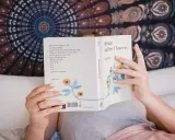 Une personne lit "the sun and her flowers" de Rupi Kaur, un livre de poésie. La dernière page d'un livre s'appelle la postface.
