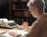 Une femme relit des manuscrits devant une machine à écrire, peut-être pour les éditions Jouvence.