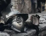 Casque de gladiateur et son épée, rappelant un prénom masculin médiéval fantastique. L'armure repose sur des pierres, prête pour le combat.