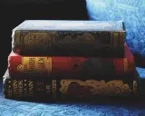 Pile de livres anciens aux couvertures ornées. Inspiré par ces reliures, découvrez comment créer la couverture d'un livre captivante.