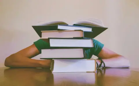 Une pile de livres sur la tête, symbolisant le poids de la connaissance et le sujet philo conscience.