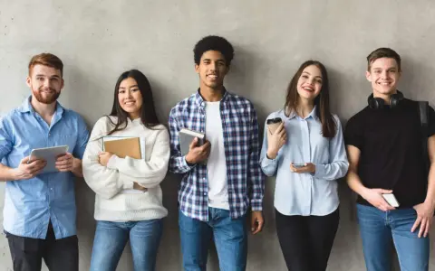 Cinq étudiants souriants, prêts pour leur grand oral STI2D. L'un tient une tablette, d'autres des livres.