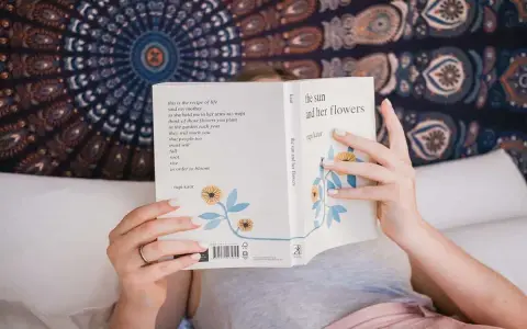 Une personne lit "the sun and her flowers" de Rupi Kaur, un livre de poésie. La dernière page d'un livre s'appelle la postface.