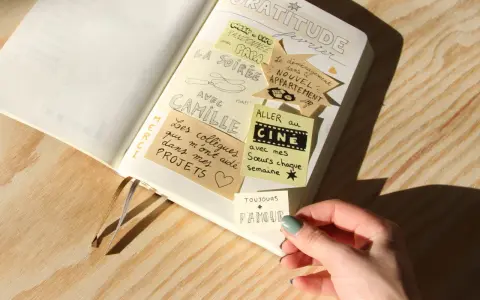 Un journal de gratitude avec des notes collées : "La soirée avec Camille", "Aller au cinéma avec mes sœurs", "Le déménagement dans le nouvel appartement".