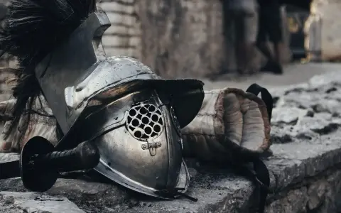 Casque de gladiateur et son épée, rappelant un prénom masculin médiéval fantastique. L'armure repose sur des pierres, prête pour le combat.