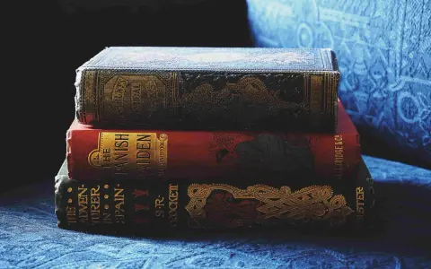 Pile de livres anciens aux couvertures ornées. Inspiré par ces reliures, découvrez comment créer la couverture d'un livre captivante.