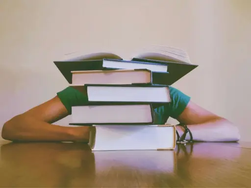 Une pile de livres sur la tête, symbolisant le poids de la connaissance et le sujet philo conscience.