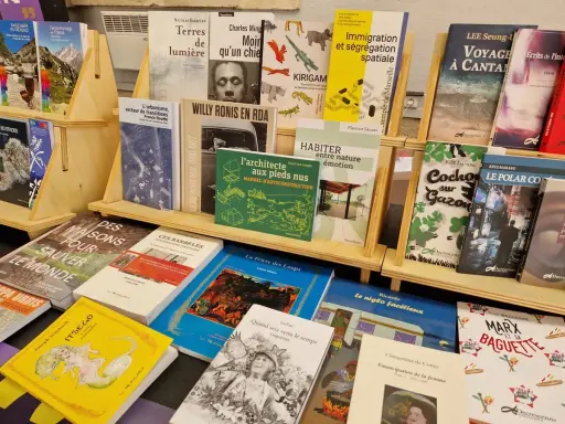 Des livres de divers éditeurs de livres, dont des ouvrages sur l'urbanisme, la photographie et la cuisine, sont exposés sur des étagères en bois.