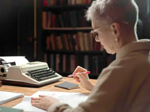 Une femme relit des manuscrits devant une machine à écrire, peut-être pour les éditions Jouvence.