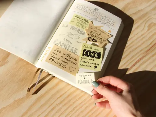 Un journal de gratitude avec des notes collées : "La soirée avec Camille", "Aller au cinéma avec mes sœurs", "Le déménagement dans le nouvel appartement".
