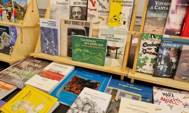 Des livres de divers éditeurs de livres, dont des ouvrages sur l'urbanisme, la photographie et la cuisine, sont exposés sur des étagères en bois.