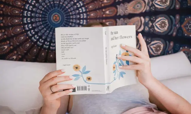 Une personne lit "the sun and her flowers" de Rupi Kaur, un livre de poésie. La dernière page d'un livre s'appelle la postface.