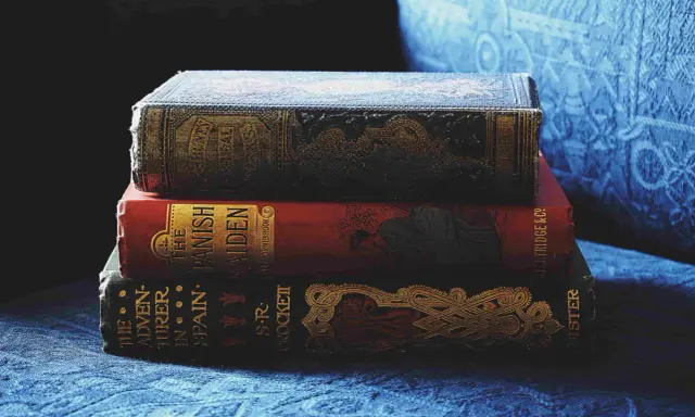 Pile de livres anciens aux couvertures ornées. Inspiré par ces reliures, découvrez comment créer la couverture d'un livre captivante.