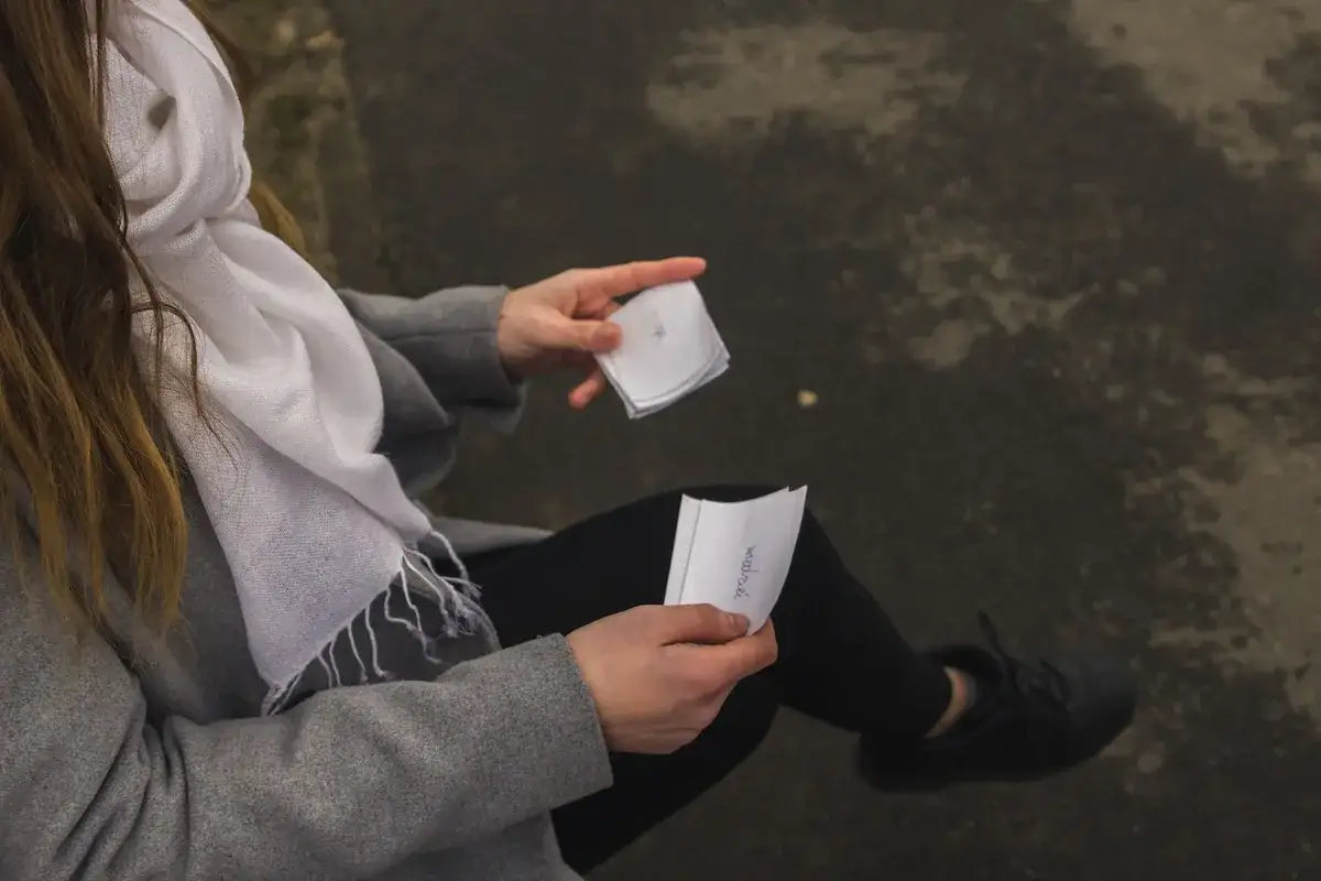 Une femme en manteau gris et &eacute;charpe blanche tient des notes pour un rattrapage m&eacute;moire.