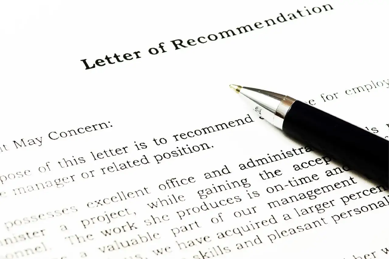 Une lettre de recommandation est pr&ecirc;te &agrave; &ecirc;tre sign&eacute;e. Un stylo argent&eacute; repose sur le document.