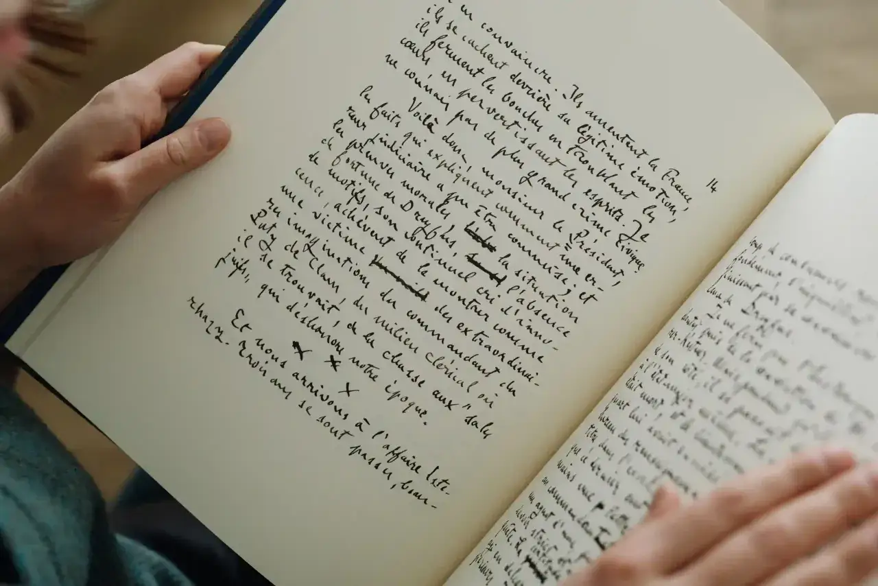 Main d'une personne tenant un jc lattès manuscrit. Le texte manuscrit est écrit à la main en français.